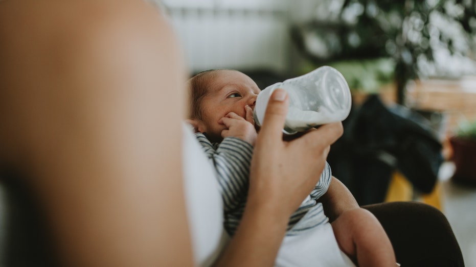 Mother gives baby milk bottle