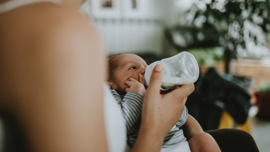 Mother gives baby milk bottle