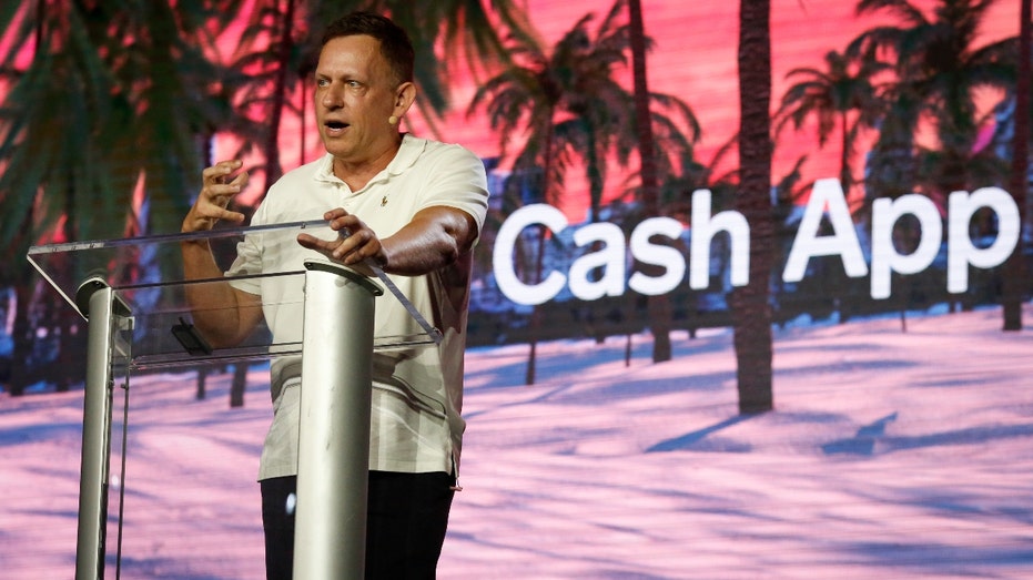 Peter Thiel, co-founder of PayPal, Palantir Technologies, and Founders Fund, holds hundred dollar bills as he speaks during the Bitcoin 2022 Conference at Miami Beach Convention Center on April 7, 2022 in Miami, Florida.