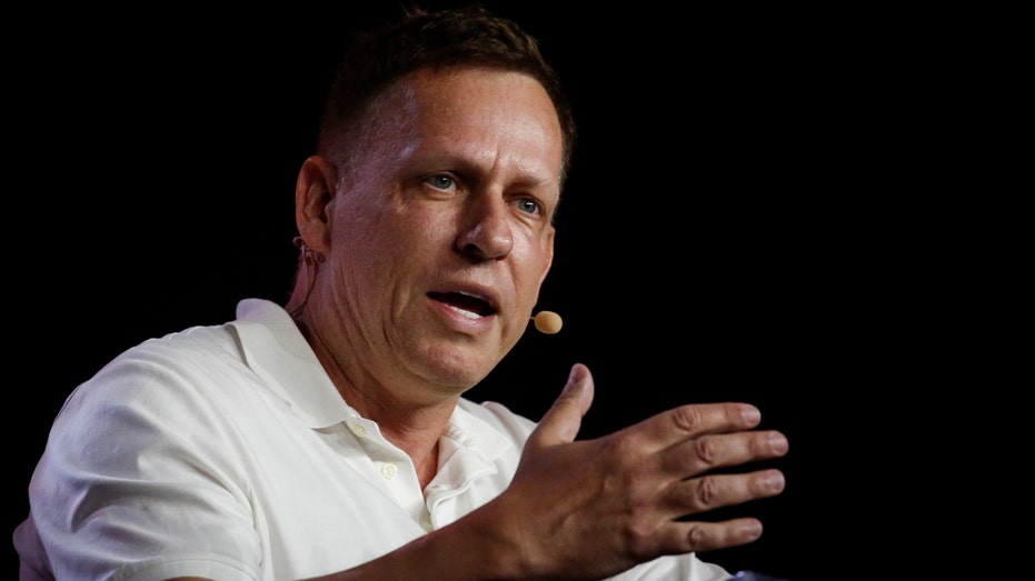 Peter Thiel, co-founder of PayPal, Palantir Technologies, and Founders Fund, holds hundred dollar bills as he speaks during the Bitcoin 2022 Conference at Miami Beach Convention Center on April 7, 2022 in Miami, Florida.