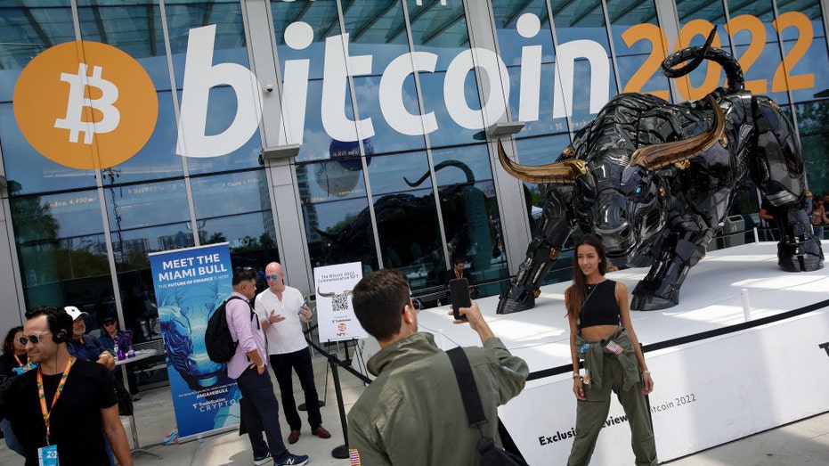 Udeleženci med Bitcoin konferenco pozirajo za fotografije pred Miami Bullom