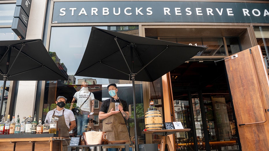FILE - Employees wearing masks pose outside the Starbucks Reserve Roastery in Chelsea, July 30, 2020 in New York City. (Photo by Alexi Rosenfeld/Getty Images)