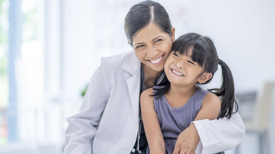 Female doctor hugs girl