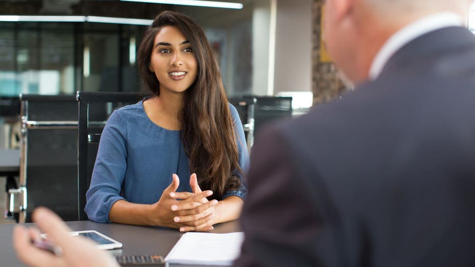 Woman speaks to man at desk