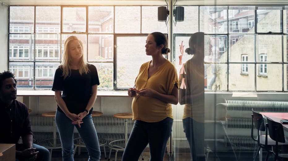 Pregnant worker standing in office