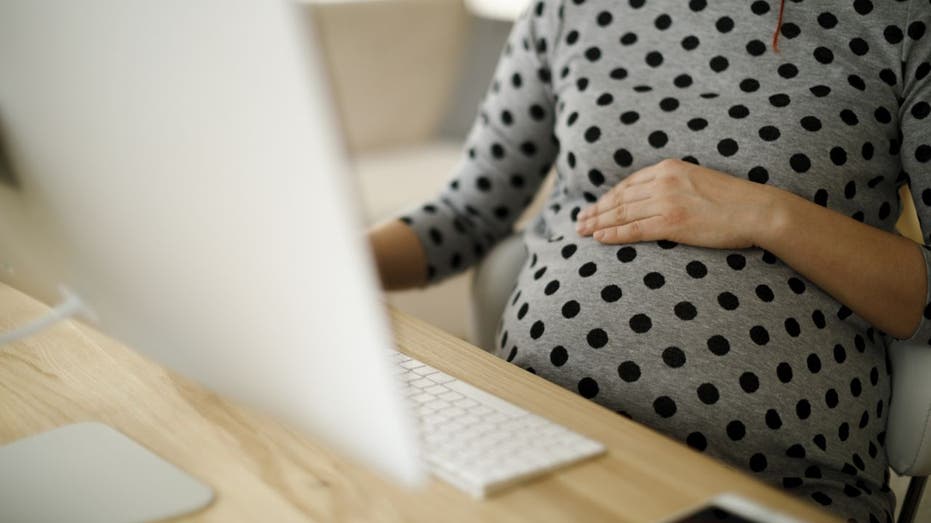 Pregnant worker at desk working on computer