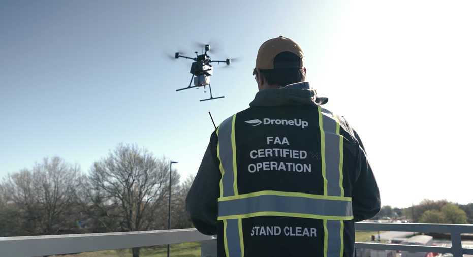 A DroneUp pilot operates a drone delivering a Walmart package