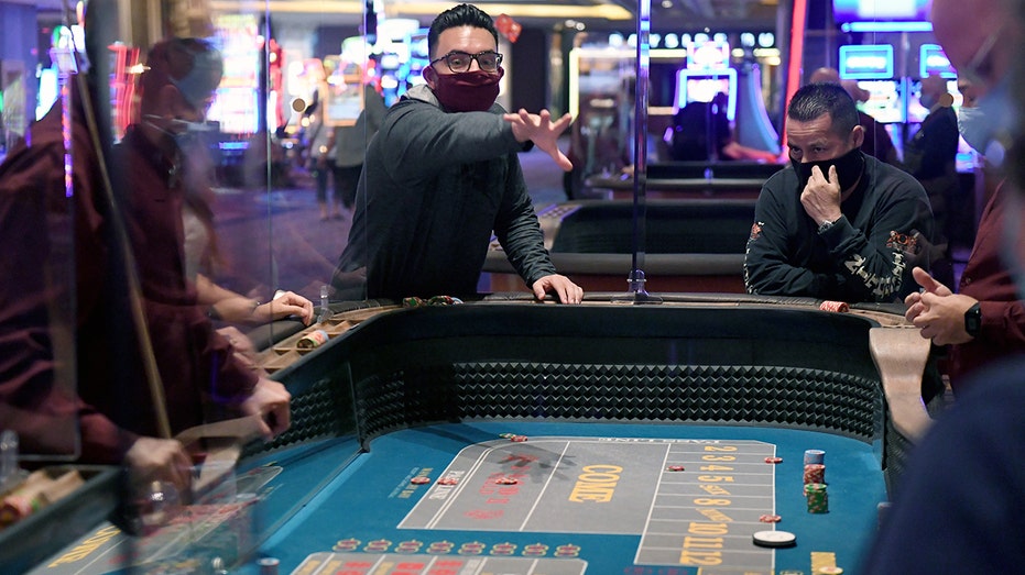 Players sit around a roulette table at a casino