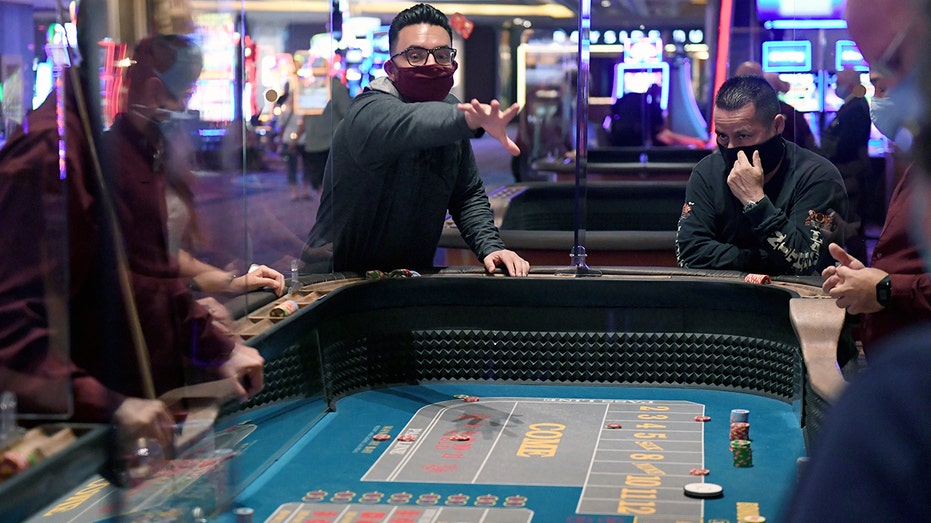 Players sit around a roulette table at a casino