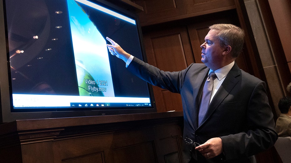 Deputy Director of Naval Intelligence points at a screening during a congressional hearing