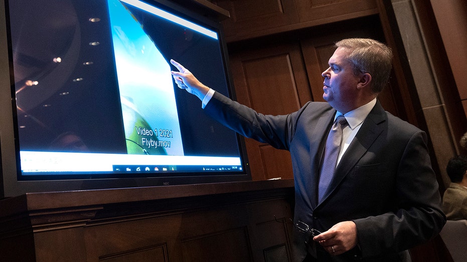 Deputy Director of Naval Intelligence points at a screening during a congressional hearing