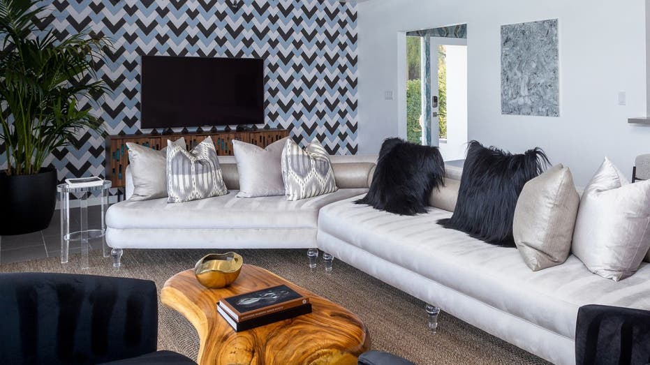 The Little Tuscany Holiday House vacation home on Vrbo is located in Palm Springs, California. This interior photo shows it has a patterned wall, wood coffee table and white sofas.