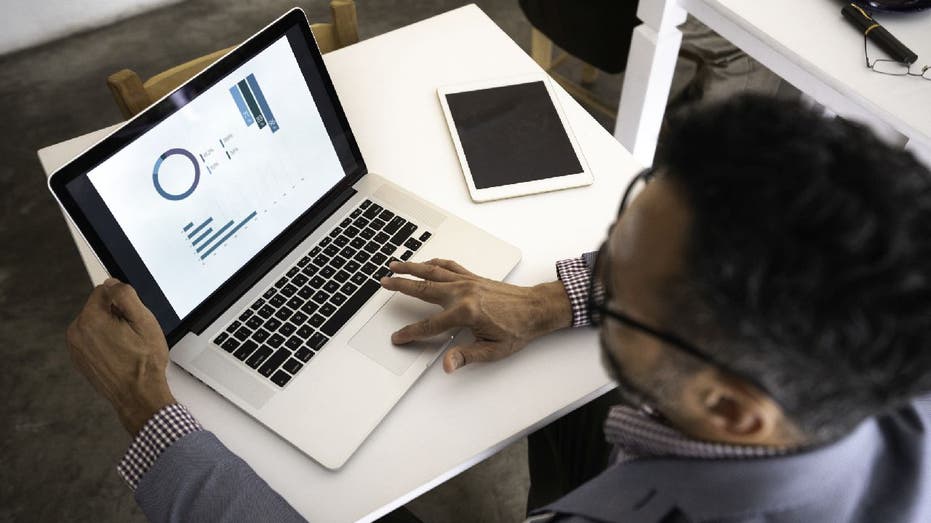 Man looks at charts on laptop