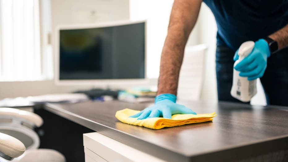 Man cleans computer desk area