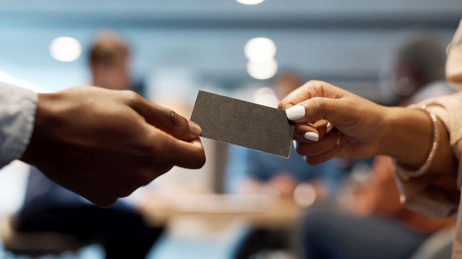 A person hands a business card to another person
