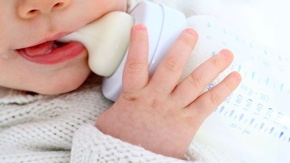 Baby drinks from milk bottle