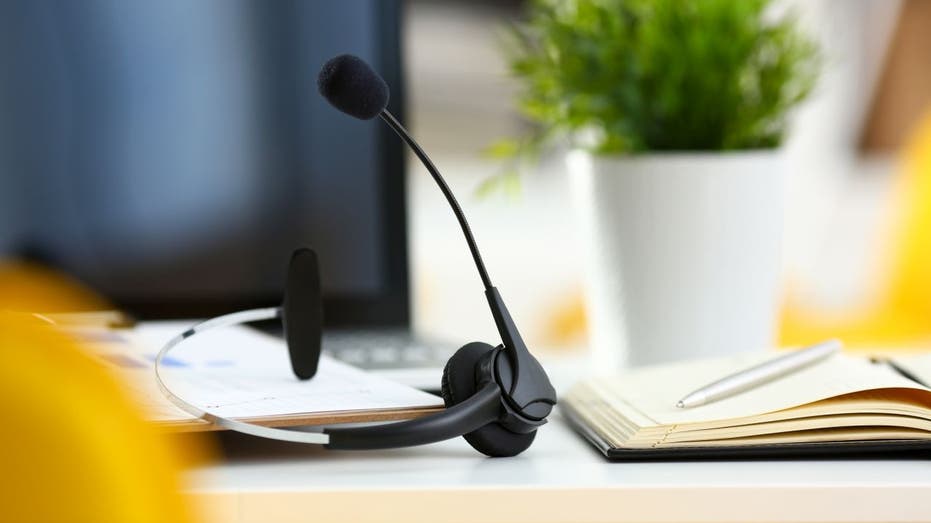 Headset near computer and a notepad with a pen on a desk