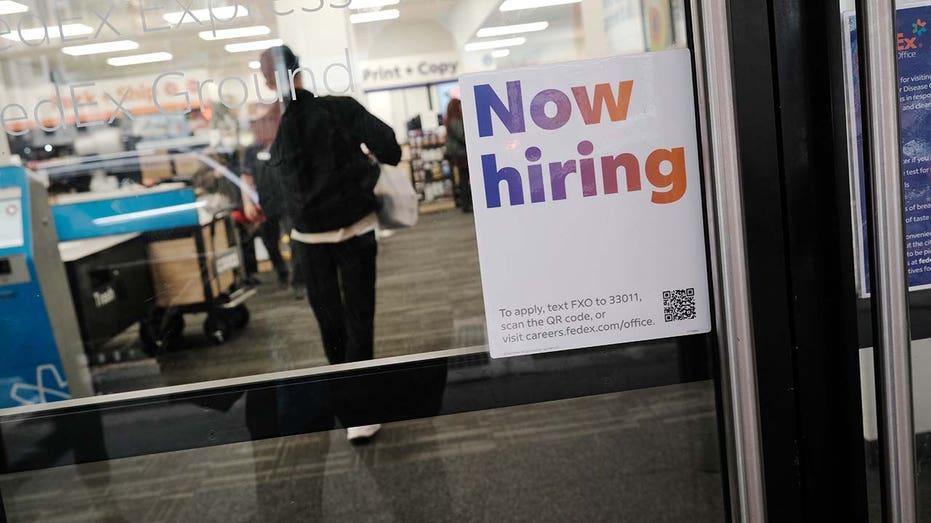 A now hiring sign on a door. 