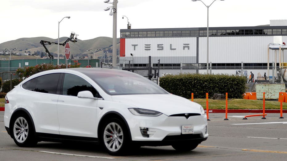 A white Tesla is driven outside a Tesla factory