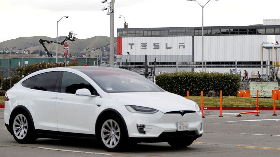 A white Tesla is driven outside a Tesla factory