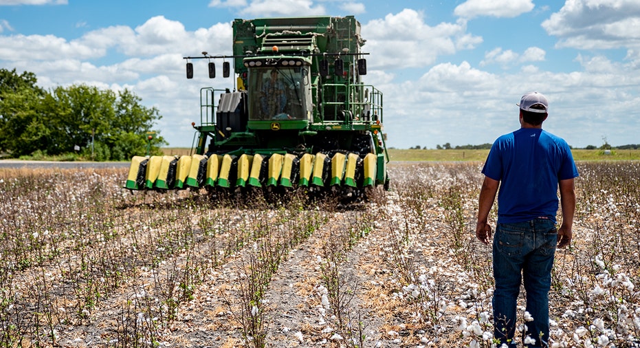 A Texas cotton farmer stands in front of a tractor