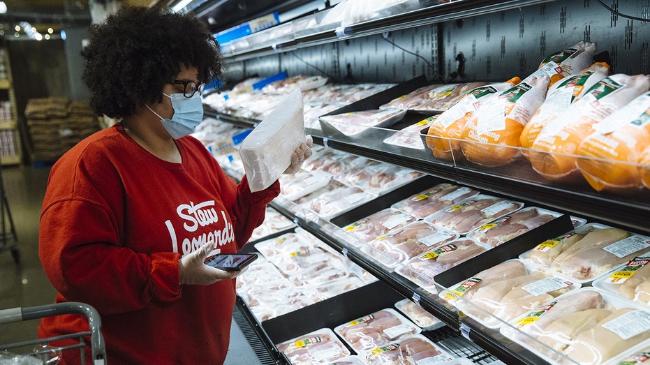 Woman looks at meat prices in store