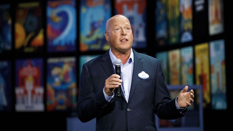 Bob Chapek of Disney speaking in a suit in front of movie posters