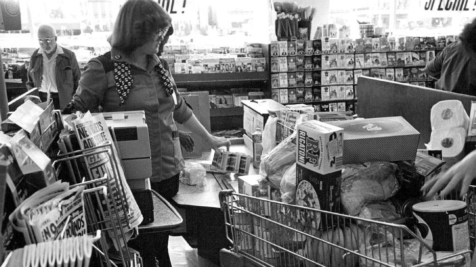 Woman at supermarket checkout with full cart