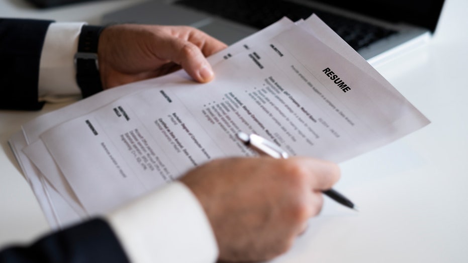 A pair of hands holds job resume and pen