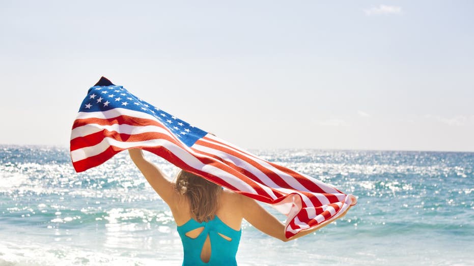 Woman holds up american flag on beach