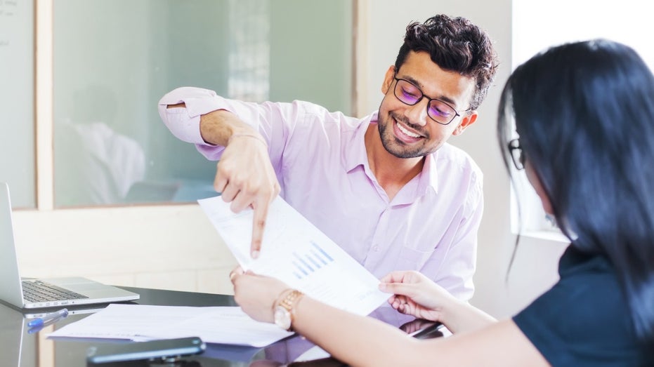 Two employees talking at desk