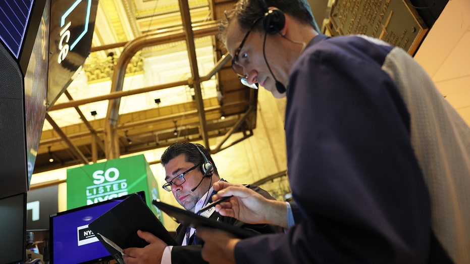 A photo of two men looking at stock market figures