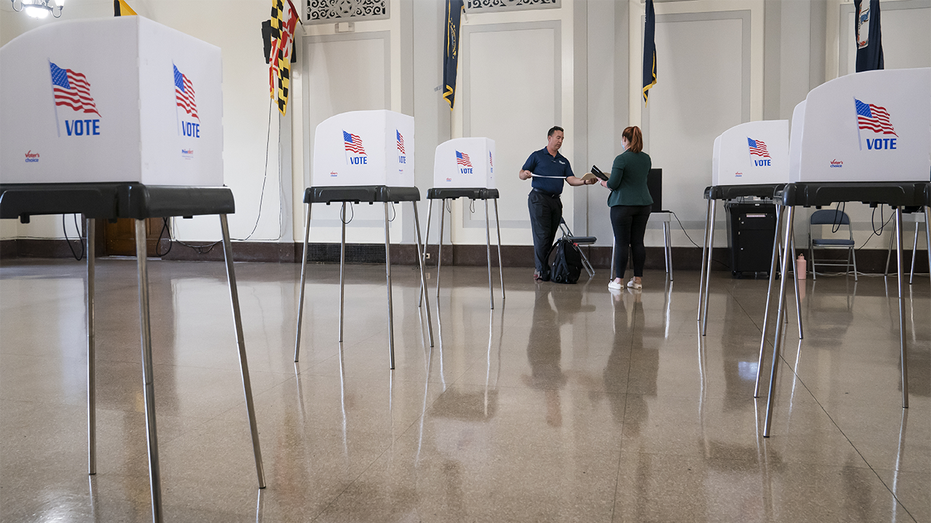 Two people stand next to voting booths