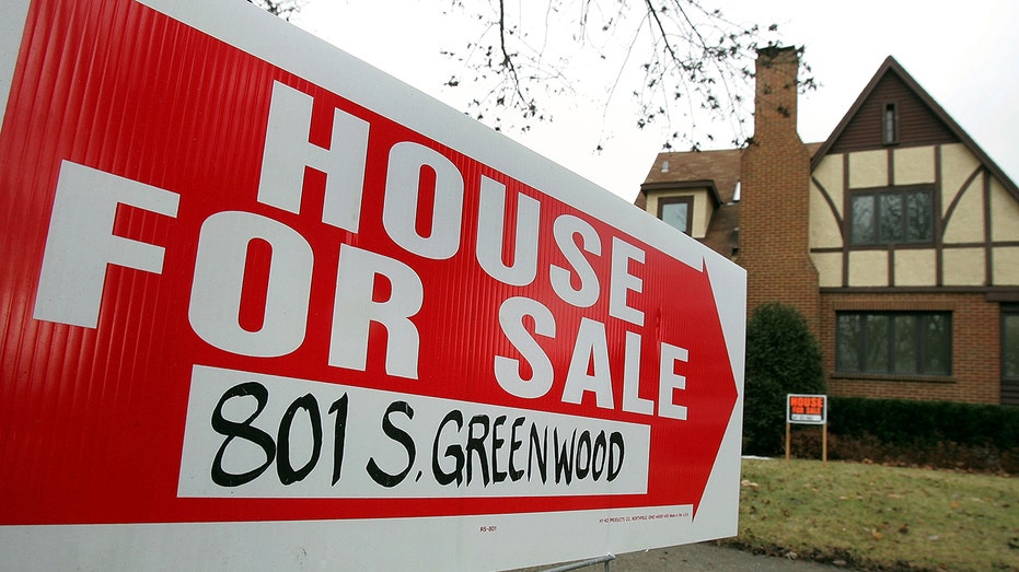 A "house for sale" sign sits outside a home