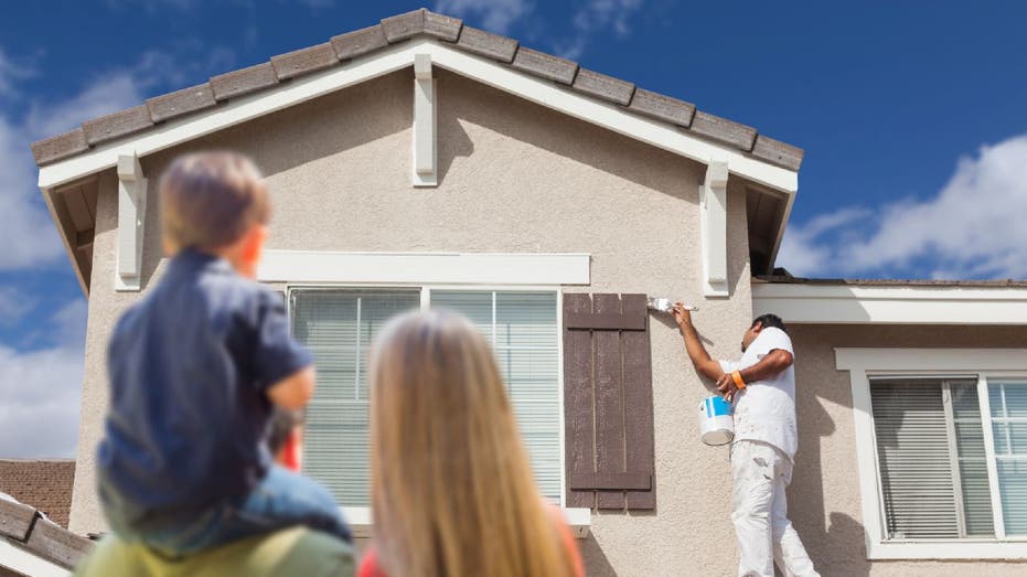 Contractor paints window while family watches