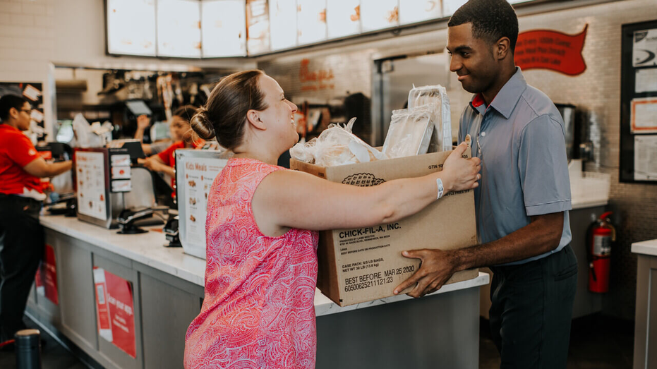 Chick-fil-A Shared Table press release promo photo shows woman grabbing box from worker