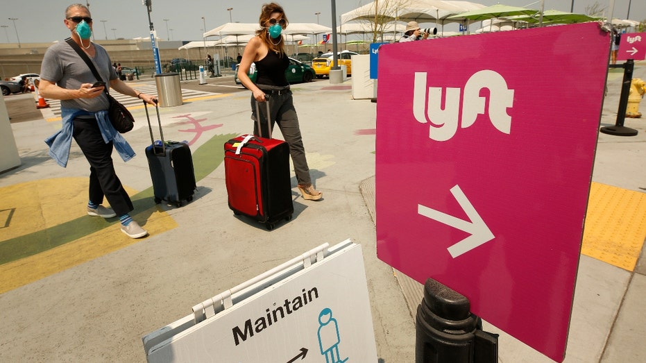 Two woman walk toward a Lyft sign