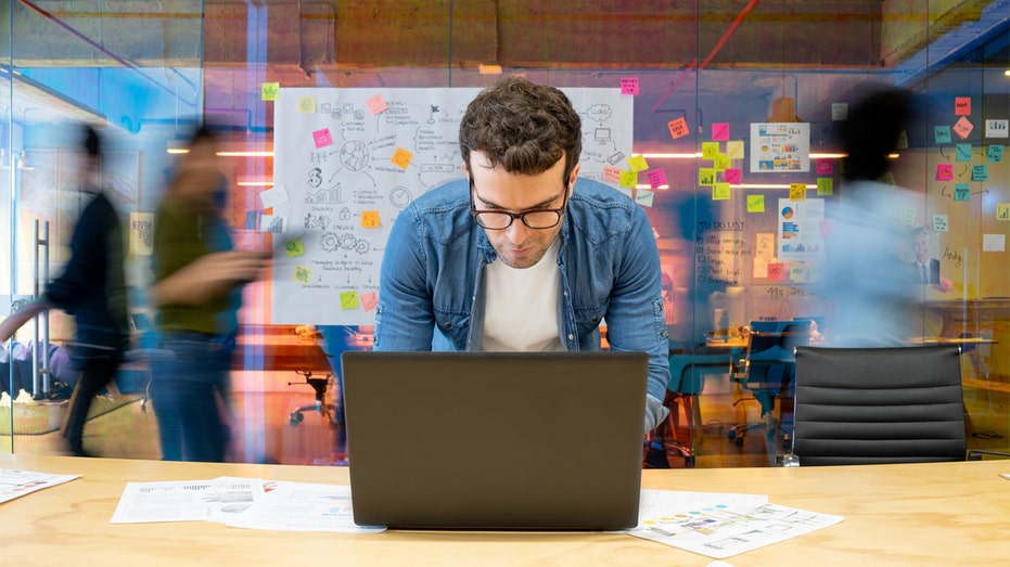 man at work bent over laptop