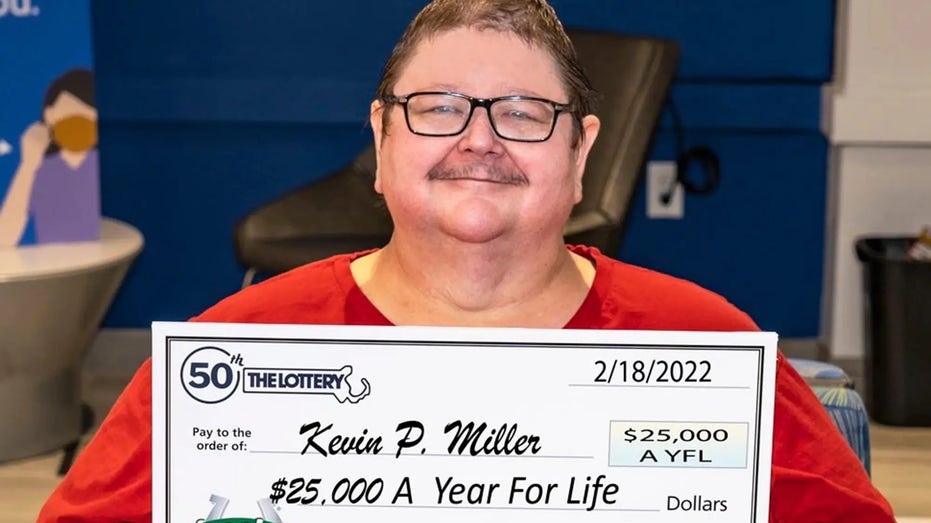 Kevin Miller holds his check for $25,000 a year for life