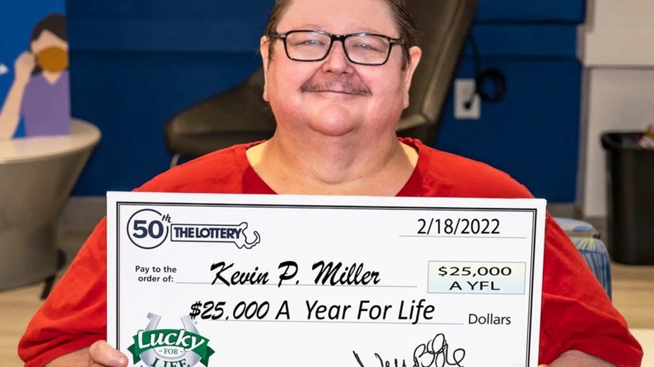 Kevin Miller holds his check for $25,000 a year for life