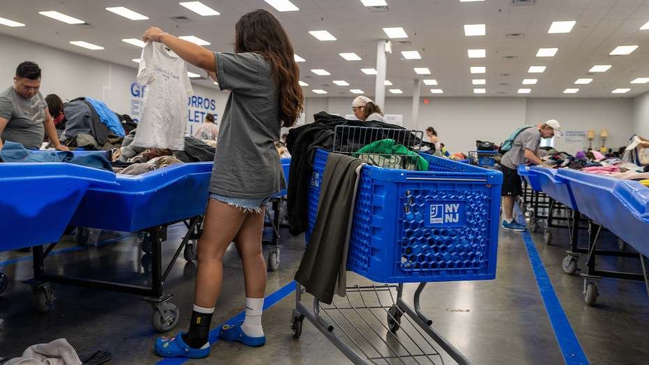 Photo of woman going through piles of clothing at thrift shop