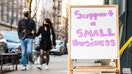 People walk by a sign that reads, &quot;support a small business&quot; outside of a store in Chelsea on March 21, 2021 in New York City. 