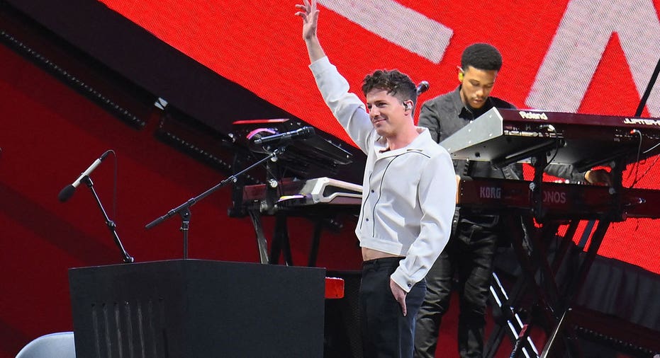 Charlie Puth holds up his hand while on stage