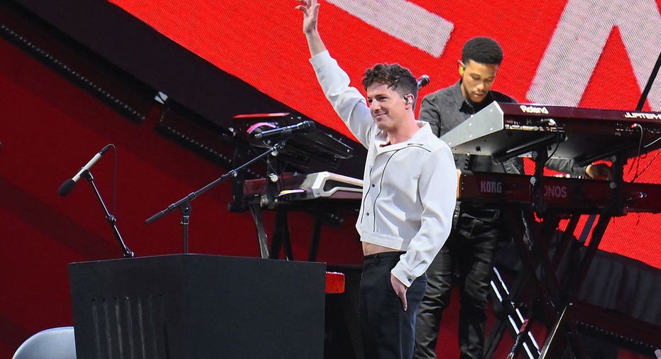 Charlie Puth holds up his hand while on stage