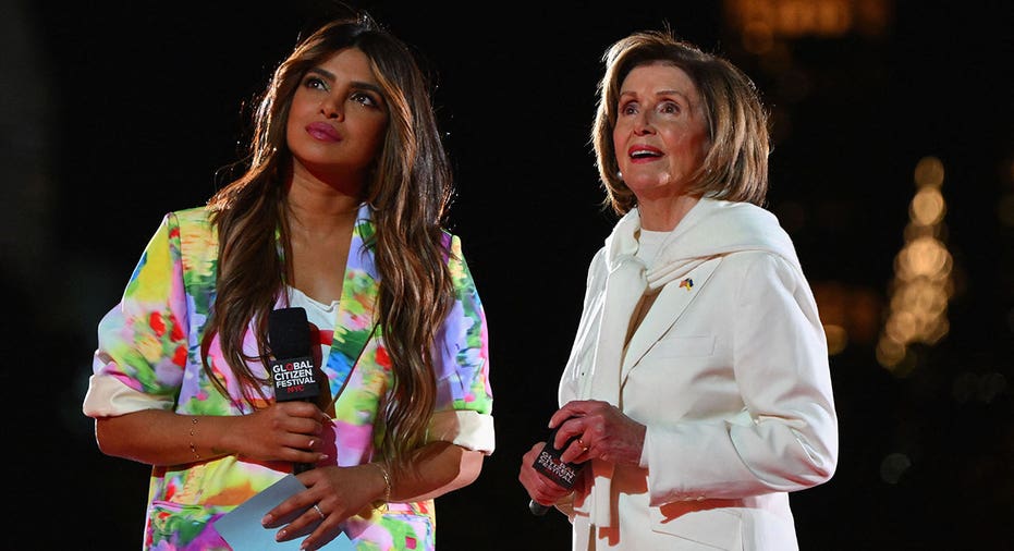 Nancy Pelosi (right) in white pant suit and Priyanka Chopra (right) in colorful top while on stage