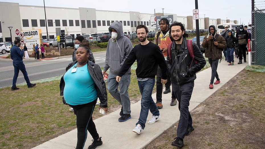 Amazon workers march in front of an Amazon warehouse