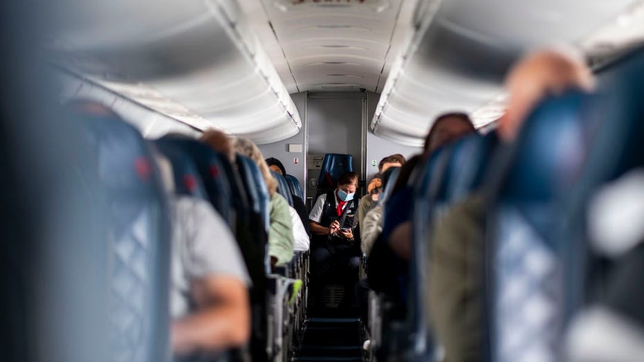 Flight attendant at end of aisle on flight