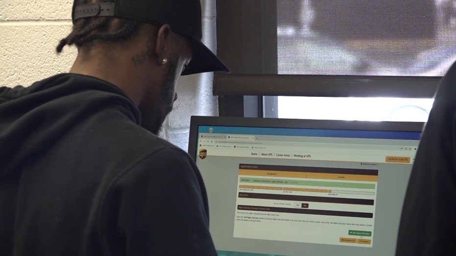 man looks at computer with job application pulled up on the screen
