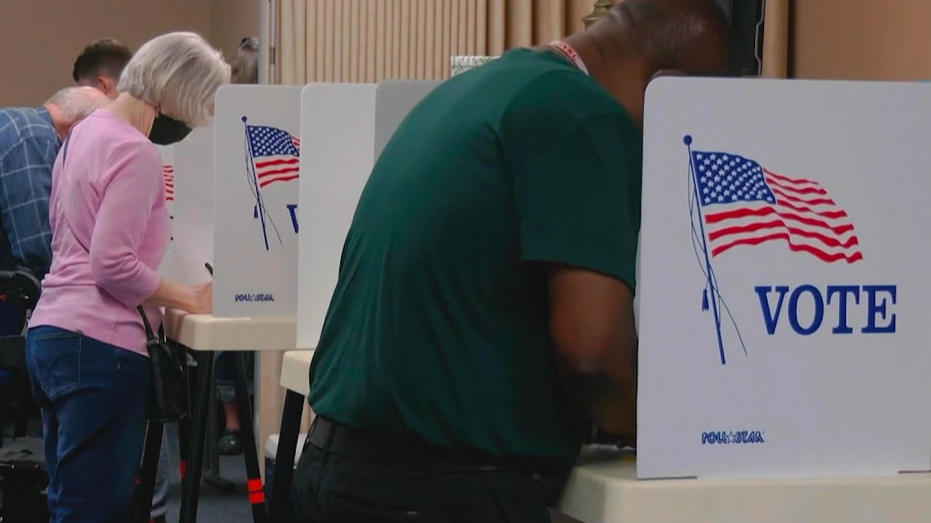 A male and female voter casting their vote at the ballot box