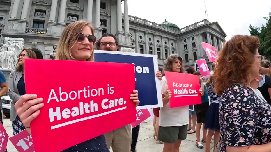 Protesters holding signs in front of the Pennsylvania State capitol. One sign reads 'Abortion is Health Care.'